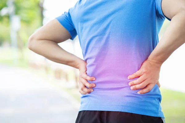 unhappy man suffering from Sport injury while exercise, with Lower back pain in the spine with back ache. people ,health care or medical and lifestyle concept. Highlighting the red color, showing pain