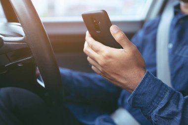Yakın görüş el memnun genç işadamı cep telefonu bakarken bir araba sürücü. ulaşım ve araç konsepti.