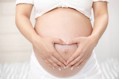 Beyaz iç çamaşırı yeni anne Hamile kadın bebek ile el dokunmatik karın göbeği kullanır. Bebek bekleyen genç kadın 