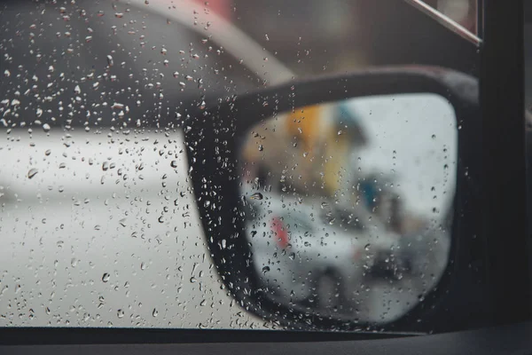 Drops Of Rain Drizzle on the glass windshield in the night. street in the heavy rain. Bokeh Tail light. soft Focus. Please drive carefully, slippery road. soft focus. traffic jam car.