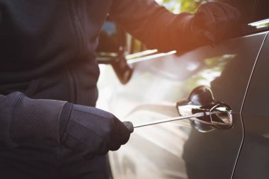 Kapalı araba hırsızı, elinde tornavida, elinde tornavida, elinde çekiç ve eldiven, araba çalarken kapı kolu, kilidi açık mı diye bakmak için. araba hırsızlığı konsepti.