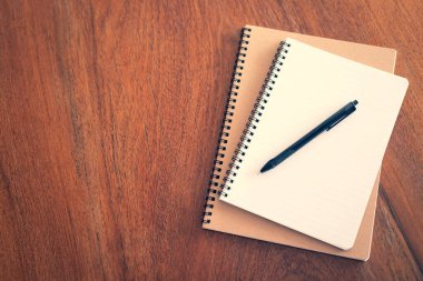 Ahşap masanın üzerinde kalem ve kalem olan defter.