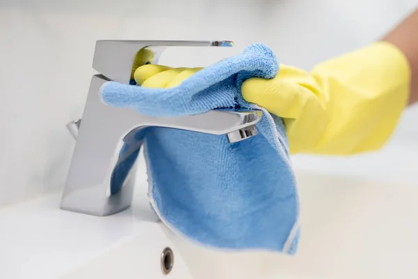 Staff is cleaning faucet in the bathroom.