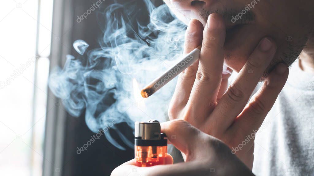 A man is smoking a cigarette at home