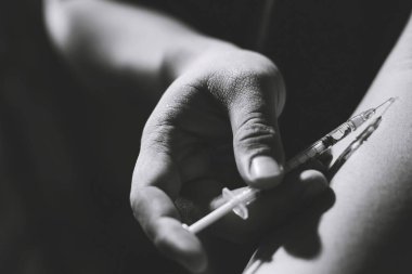 Elinde uyuşturucu şırıngası tutan keş bir adam. Eroin enjekte ediyor. 