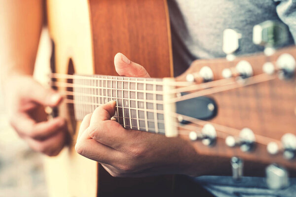 Man's hands playing acoustic guitar