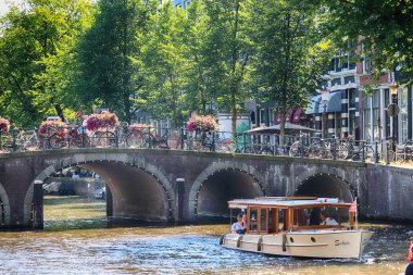 Amsterdam, Hollanda - 08 Temmuz 2018: Yaz aylarında teknelerle Canal. Eski Amsterdam tarihi evlerde. Tipik Hollanda Mimarlık.