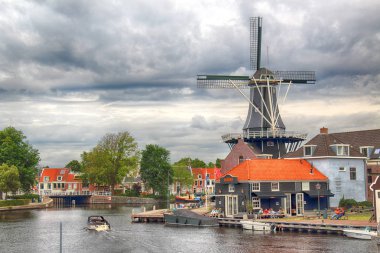 Haarlem, Hollanda - 09 Temmuz 2018: Yel değirmeni Adriaan ile Spaarne nehir ve güzel bulutlar. Tipik Hollanda Mimarlık.