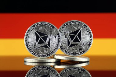 Ethereum (Eth) ve Almanya bayrağı fiziksel sürümü. Blockchain teknolojisi, akıllı sözleşmeler, kişisel belirteçleri ve ilk para sunan cryptocurrency, yatırımcılar için kavramsal görüntü.