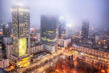 Varşova, Polonya - 4 Kasım 2018: Varşova, Polonya'nın şehir merkezi bölgesinde Modern gökdelenler. Sisli gece boyunca havadan görünümü.