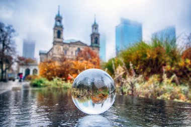 WARSAW, POLAND - NOVEMBER 3, 2018: Grzybowski Square is a triangular square in the downtown district of Warsaw, Poland. View through a glass, crystal ball (lensball) for refraction photography. clipart