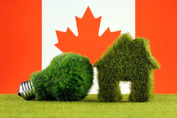 Green eco light bulb, eco house icon and Canada Flag. Renewable energy. Electricity prices, energy saving in the household.