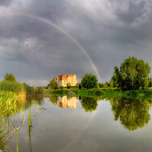 Beautiful rainbow and storm clouds over the lake, on the last day of spring, in Biskupice Podgorne near Wroclaw, Poland.