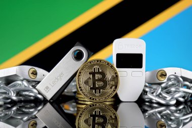 Wroclaw, Polonya - 06 Temmuz 2019: Bitcoin (Btc), Trezor ve Ledger (cryptocurrency donanım cüzdanları), asma kilitler, zincir (Blockchain Teknolojisi gibi) ve Tanzanya Bayrağı'nın fiziksel sürümü.