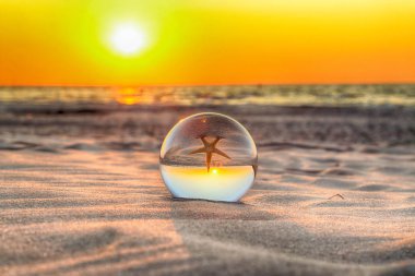 Leba, Polonya yakınlarındaki Slowinski Milli Parkı'nda plajda güzel gün batımı. Bir cam, kristal top (lensball) kırılma fotoğraf için bir denizyıldızı görünümü. Vahşi, el değmemiş doğa.