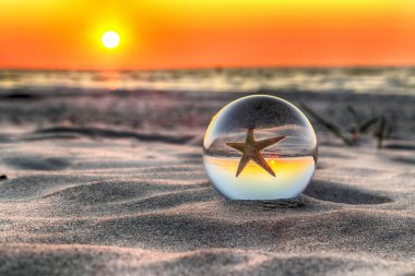 Leba, Polonya yakınlarındaki Slowinski Milli Parkı'nda plajda güzel gün batımı. Bir cam, kristal top (lensball) kırılma fotoğraf için bir denizyıldızı görünümü. Vahşi, el değmemiş doğa.