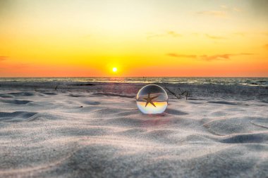 Leba, Polonya yakınlarındaki Slowinski Milli Parkı'nda plajda güzel gün batımı. Bir cam, kristal top (lensball) kırılma fotoğraf için bir denizyıldızı görünümü. Vahşi, el değmemiş doğa.
