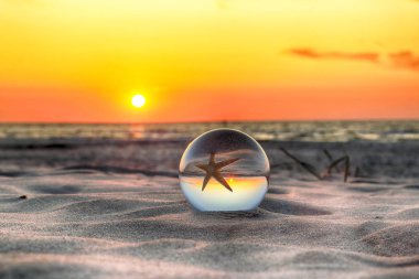 Leba, Polonya yakınlarındaki Slowinski Milli Parkı'nda plajda güzel gün batımı. Bir cam, kristal top (lensball) kırılma fotoğraf için bir denizyıldızı görünümü. Vahşi, el değmemiş doğa.