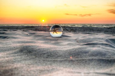 Leba, Polonya yakınlarındaki Slowinski Milli Parkı'nda plajda güzel gün batımı. Bir cam, kristal top (lensball) kırılma fotoğraf için bir denizyıldızı görünümü. Vahşi, el değmemiş doğa.