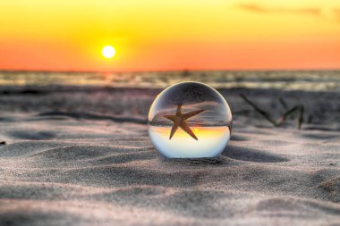 Leba, Polonya yakınlarındaki Slowinski Milli Parkı'nda plajda güzel gün batımı. Bir cam, kristal top (lensball) kırılma fotoğraf için bir denizyıldızı görünümü. Vahşi, el değmemiş doğa.
