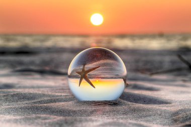 Leba, Polonya yakınlarındaki Slowinski Milli Parkı'nda plajda güzel gün batımı. Bir cam, kristal top (lensball) kırılma fotoğraf için bir denizyıldızı görünümü. Vahşi, el değmemiş doğa.