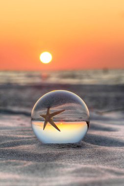 Leba, Polonya yakınlarındaki Slowinski Milli Parkı'nda plajda güzel gün batımı. Bir cam, kristal top (lensball) kırılma fotoğraf için bir denizyıldızı görünümü. Vahşi, el değmemiş doğa.
