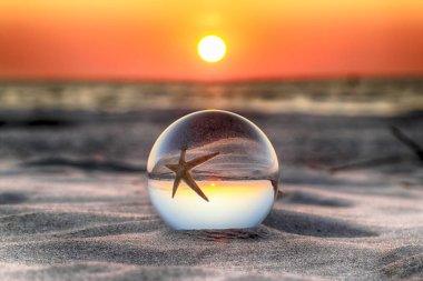 Leba, Polonya yakınlarındaki Slowinski Milli Parkı'nda plajda güzel gün batımı. Bir cam, kristal top (lensball) kırılma fotoğraf için bir denizyıldızı görünümü. Vahşi, el değmemiş doğa.