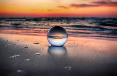 Leba, Polonya yakınlarındaki Slowinski Milli Parkı'nda plajda güzel gün batımı. Kırılma fotoğrafçılığı için bir cam, kristal küre (lensball) ile görüntüle. Vahşi, el değmemiş doğa.