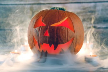 Balkabağı feneri ve ahşap arka planda mumlar sisli manzarada. Cadılar Bayramı balkabağı arka planı, duvar kağıdı.