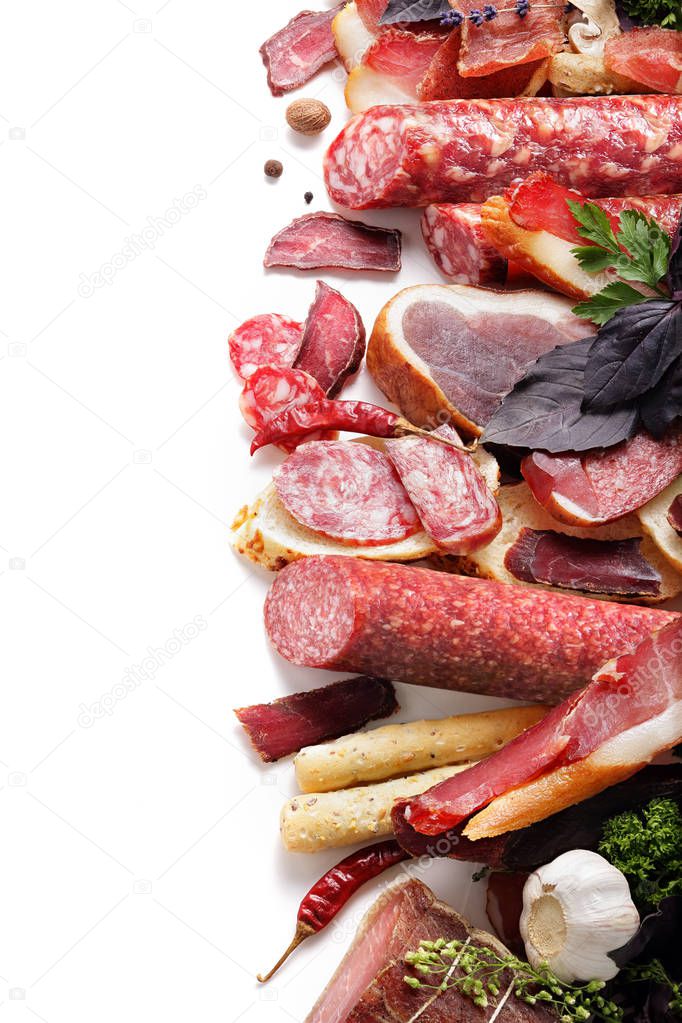 assortment of meat products including sausage ham bacon spices garlic on a white background isolated view from the top