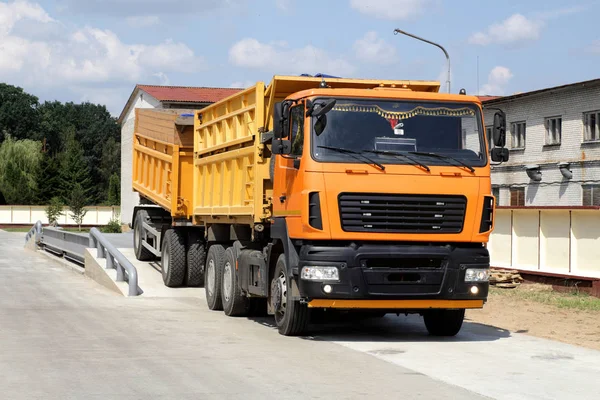 Im Getreidelager wird ein orangefarbener Lastwagen mit Getreide auf der Waage gewogen. LKW-Waage — Stockfoto