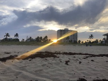 Sahilde bir binanın arkasındaki Sunburst