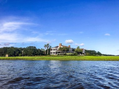 Beautiful summer day on Shem's Creek looking at Southern white mansion and the swamp clipart