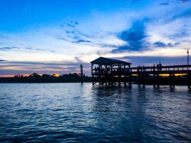 Günbatımında bir havuzda bataklık üzerinde yürüyen insanlar silüeti