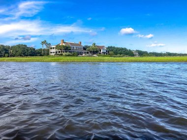 Beautiful summer day on Shem's Creek looking at Southern white mansion and the swamp clipart