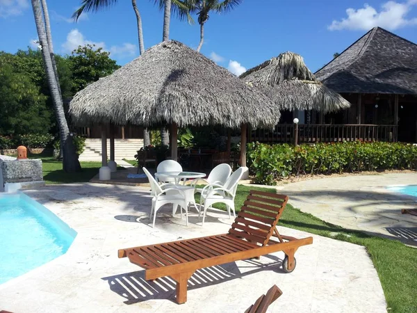 tropik tiki kulübe ve bir havuz tarafından şezlong