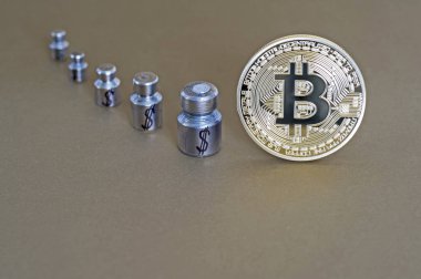 Ağırlıklar ile Bitcoin ve doları, büyüme ve düşüş gösteren sembollerin kazınmış.