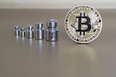 Ağırlıklar ile Bitcoin ve doları, büyüme ve düşüş gösteren sembollerin kazınmış.