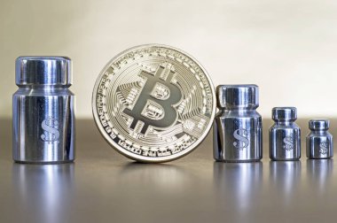 Ağırlıklar ile Bitcoin ve doları, büyüme ve düşüş gösteren sembollerin kazınmış.