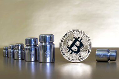 Ağırlıklar ile Bitcoin ve doları, büyüme ve düşüş gösteren sembollerin kazınmış.