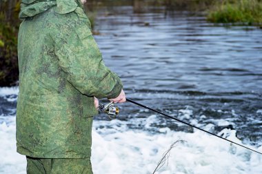Erkek fener bir iplik makara sezon hızlı suda balık yakalar. Bobin ve fener closeup eller.
