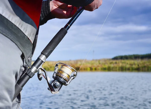 Un pescador atrapa un pez. Primer plano del carrete giratorio. Profundidad superficial del campo en el carrete de la línea de pesca — Foto de Stock