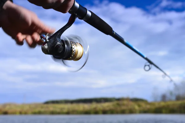 Un pescador atrapa un pez. Primer plano del carrete giratorio. Borroso. . — Foto de Stock