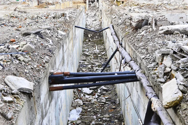 Remains of the destroyed industrial building in the form of a tunnel and laid mines cable.