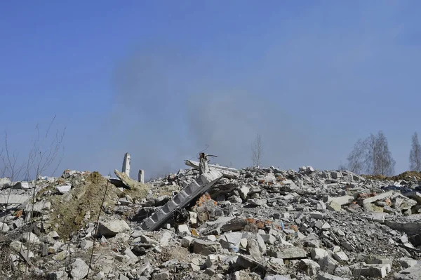 O vergalhão que se levanta de pilhas de escombros de tijolo, pedra e detritos de construção de concreto no fundo de fumaça — Fotografia de Stock