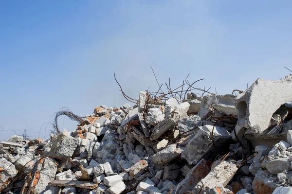 La barra de refuerzo sobresaliendo de montones de escombros de ladrillo. En el fondo, se pueden ver los restos de los clubes de humo —  Fotos de Stock