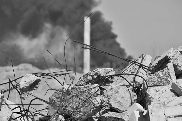 在天空中浓密的黑烟背景下突出钢筋的混凝土碎石桩 人类活动后果的概念 黑白图像 — 图库照片