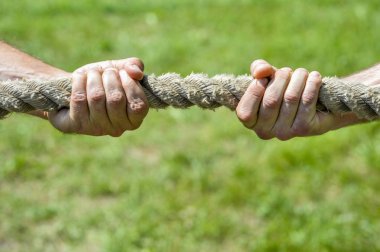 İki adamın eli ipi kendi yönüne çeker. Tartışma, çatışma ve güç kavramı