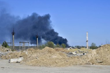 İnşaat demiri arka planda kalın siyah duman mavi gökyüzünde çıkıntılı beton moloz yığını. Arka plan. İnsan faaliyetlerinin sonuçlarını kavramı.