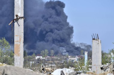 İnşaat demiri arka planda kalın siyah duman mavi gökyüzünde çıkıntılı beton moloz yığını.